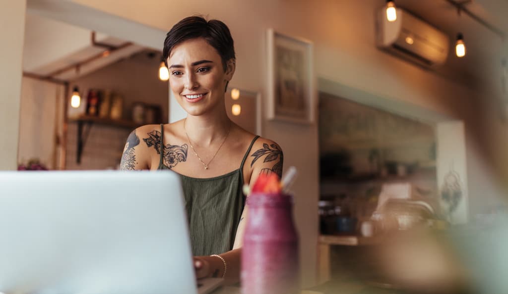 tattooed girl using laptop to write and optimize a blog post