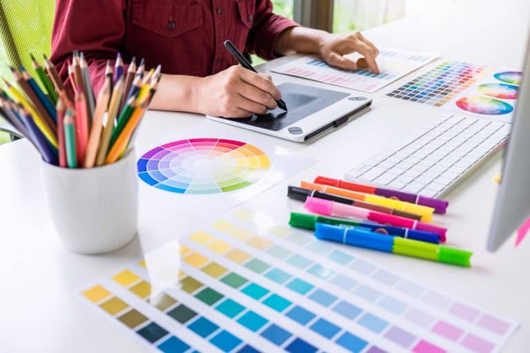 a closeup view of a designer drawing with several color palletes on the desk