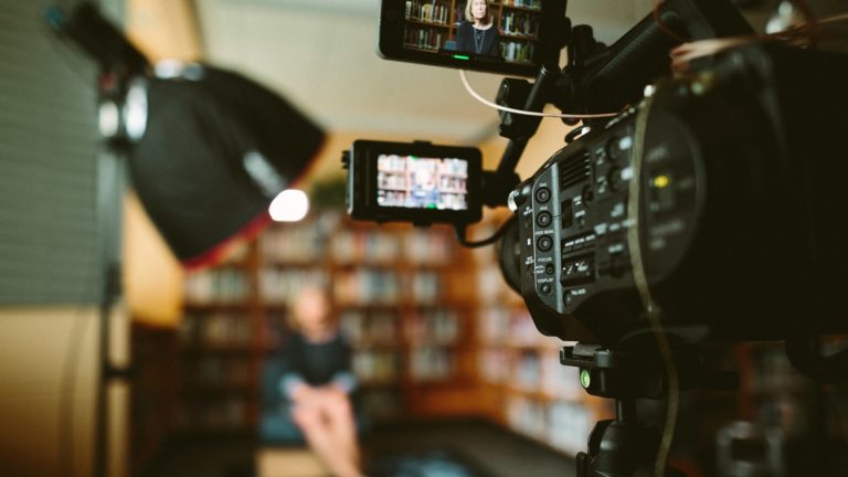 a closeup view of a camera recording an interview in a library room