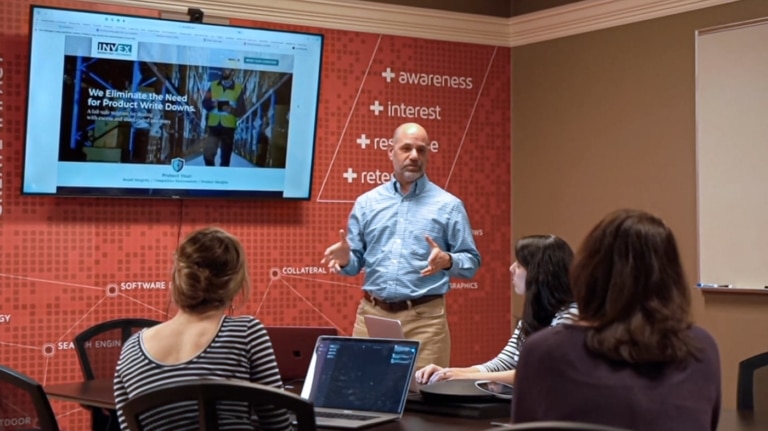 a meeting room with 3 clients listening to a presenter