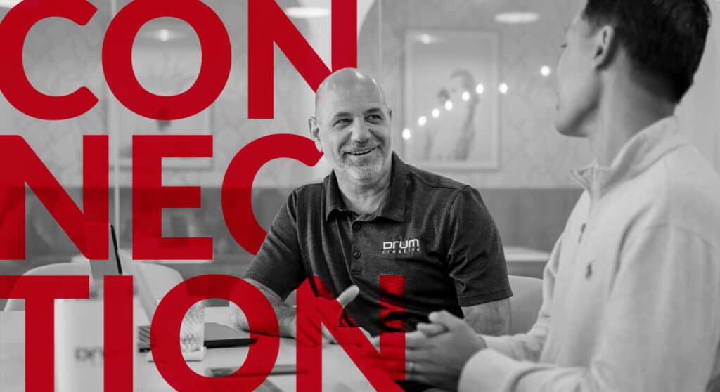two coworkers talking at a table with the word "connection" in red in the background