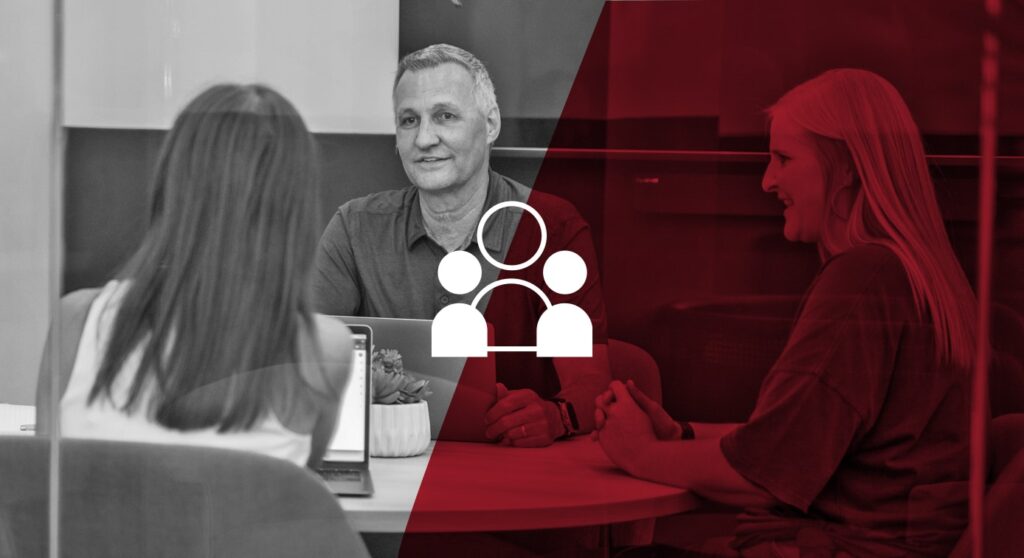 three coworkers talking and smiling while sitting together at a table