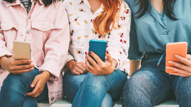 three girls watching facebook videos on iPhones