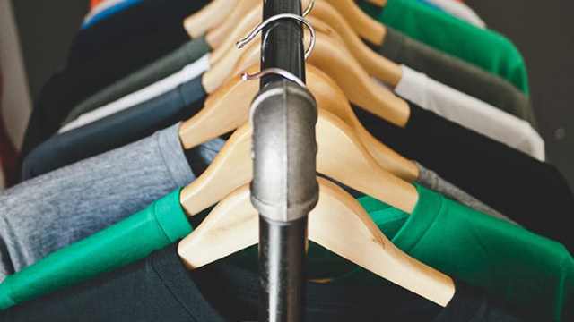 a clothing rack with a color assortment of t-shirts hanging on it