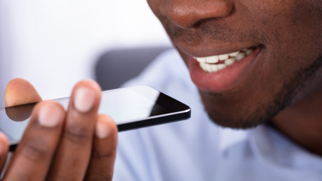 close up of man's mouth using iPhone to do voice search for a web design company near him